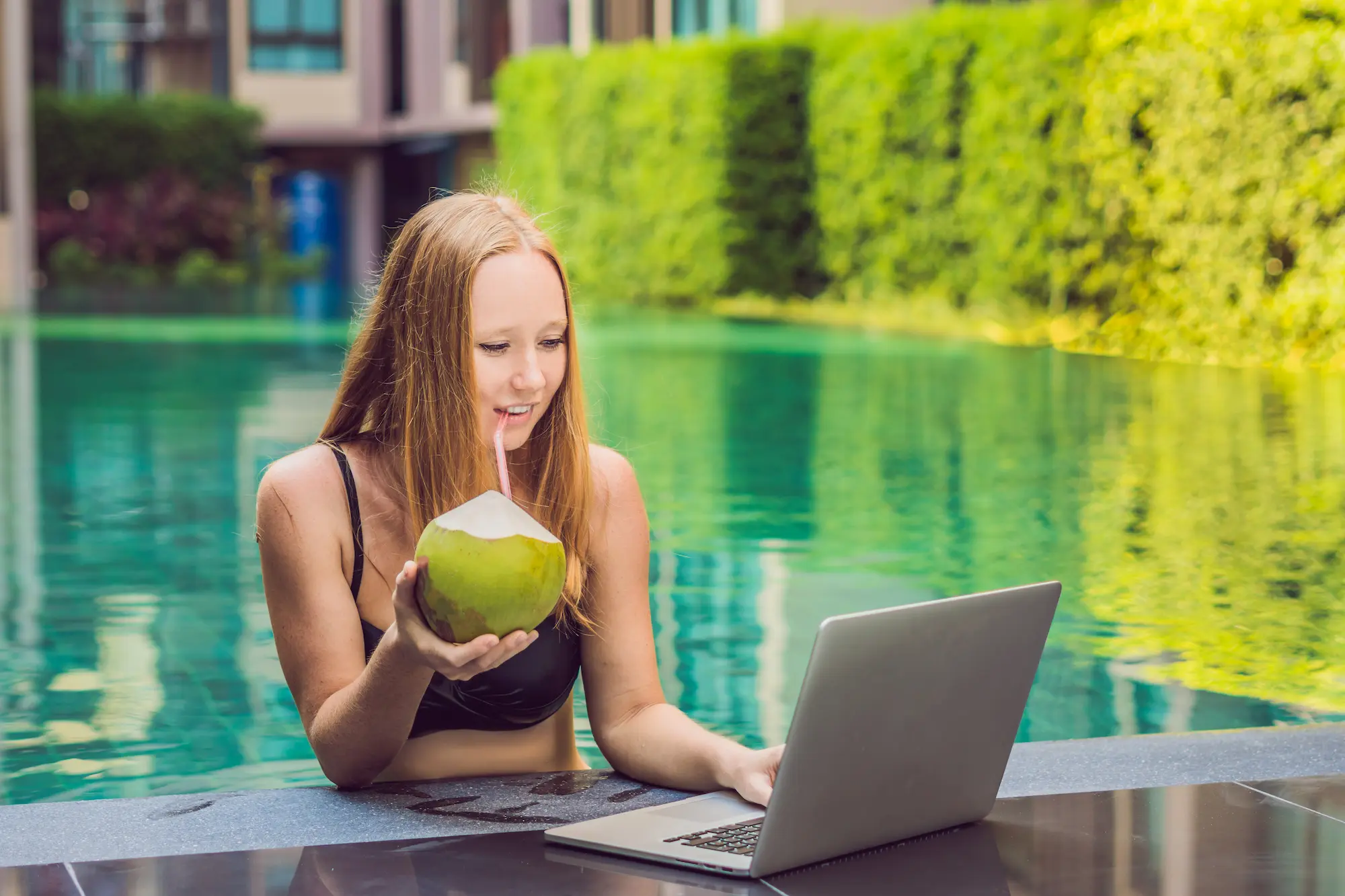 Junge Österreicherin arbeitet am Laptop am Pool in Thailand – entspanntes Arbeiten im Urlaub dank eSIM Thailand