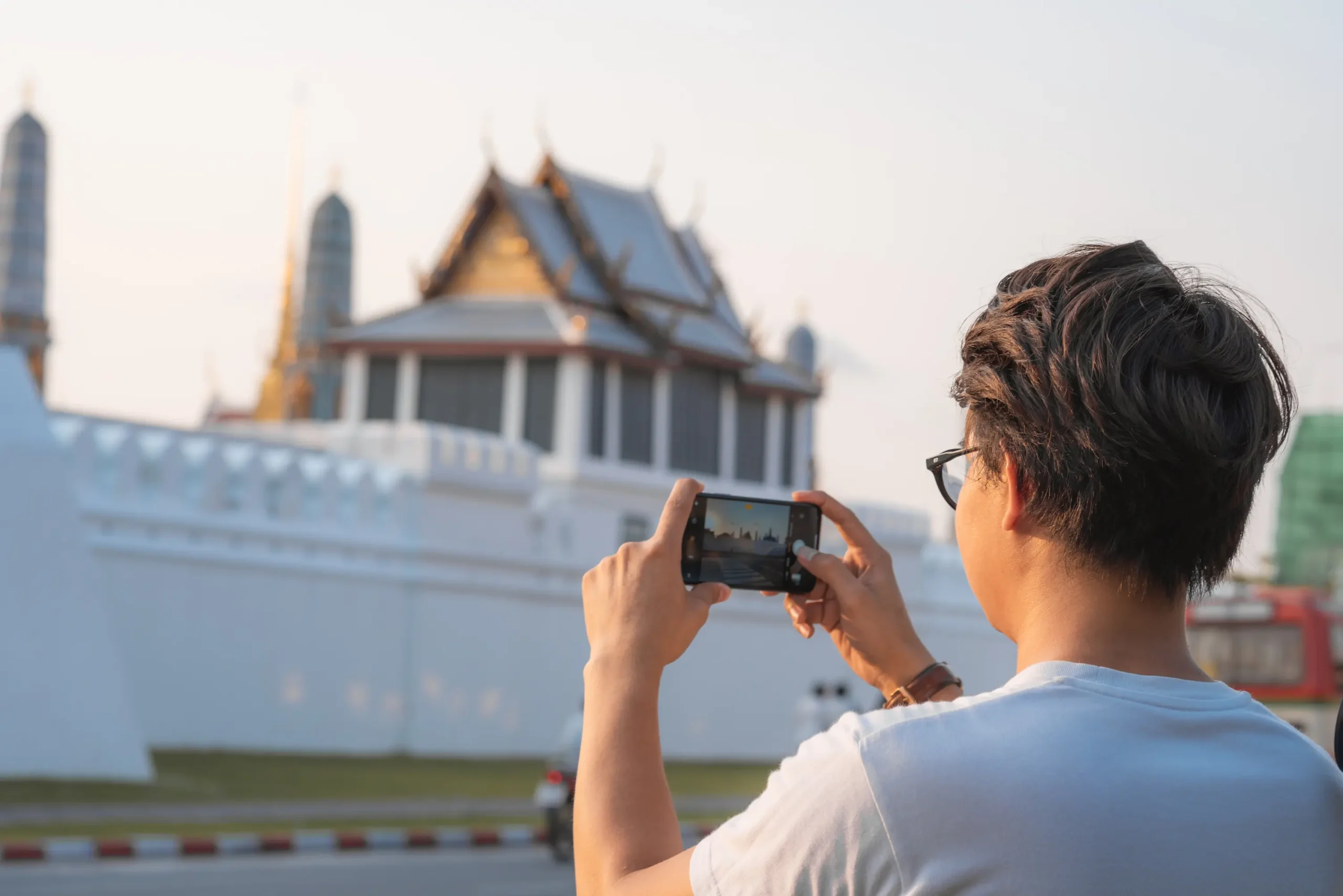 Reisender in Bangkok fotografiert Sehenswürdigkeiten mit dem Handy – unterwegs mit eSIM Thailand, ideal für österreichische Touristen